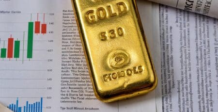 Złota sztabka na tle wykresów finansowych